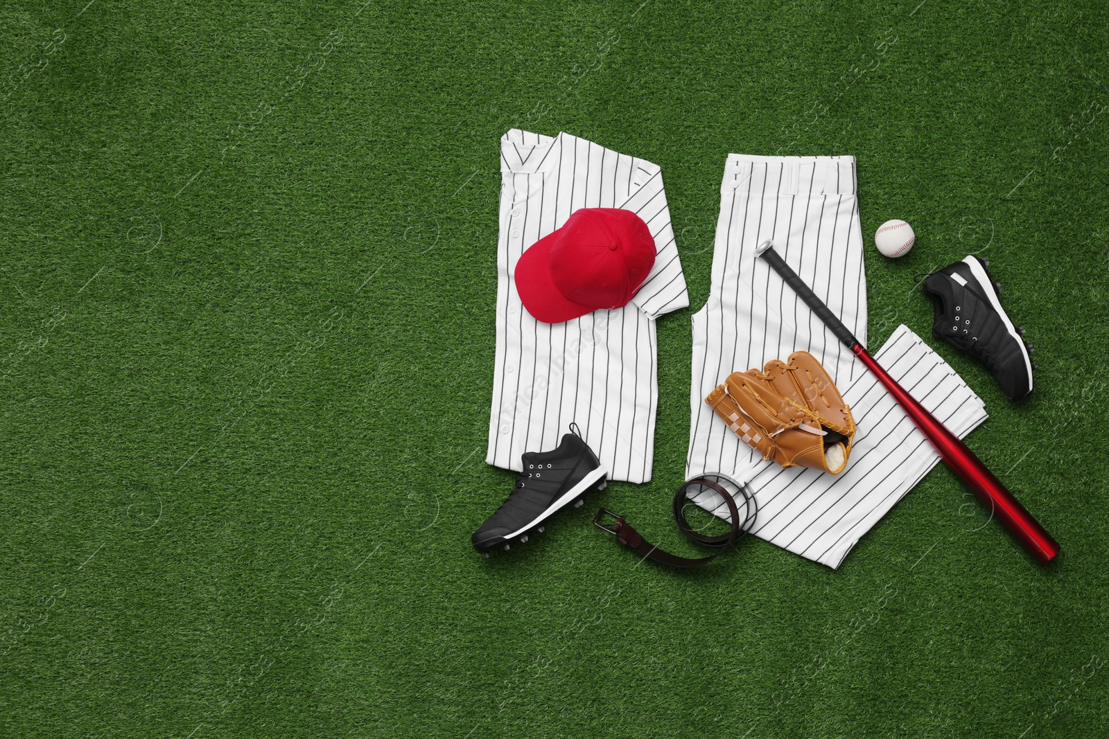 Photo of Baseball uniform and other sports equipment on artificial grass, flat lay. Space for text