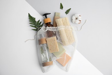 Photo of Mesh bag with eco friendly personal care products on color background, flat lay