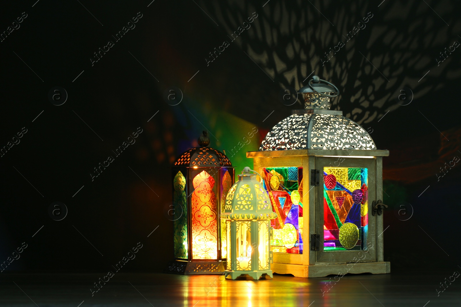 Photo of Decorative Arabic lanterns on table against dark background. Space for text