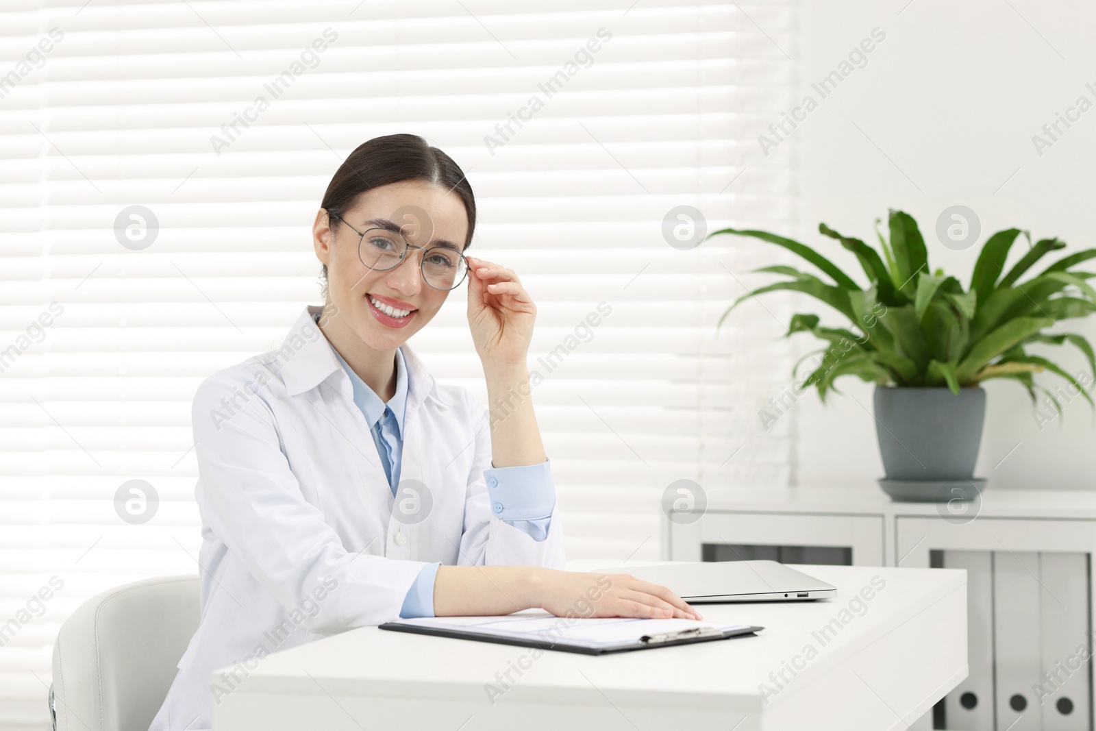 Photo of Medical consultant with glasses at table in clinic