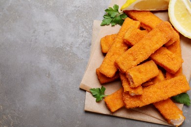 Photo of Fresh breaded fish fingers served on grey table, top view. Space for text