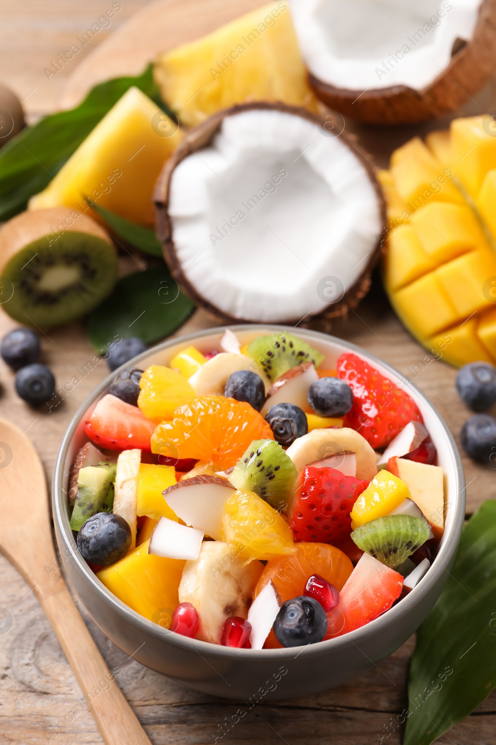 Photo of Delicious fresh fruit salad in bowl on wooden table