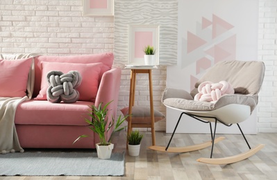 Photo of Stylish living room interior with sofa and rocking armchair near brick wall