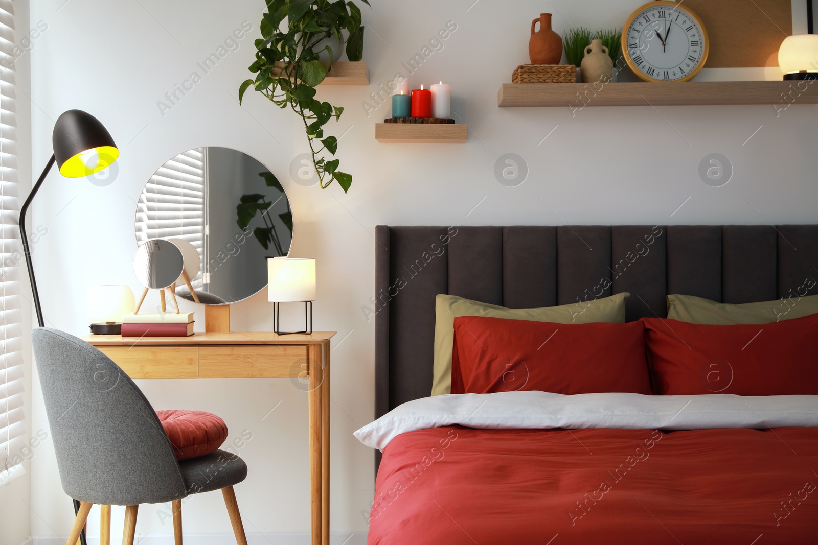 Photo of Stylish bedroom interior with comfortable bed, dressing table, lamps and green houseplant