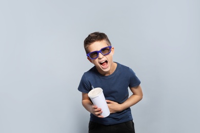 Boy with 3D glasses and beverage during cinema show on grey background