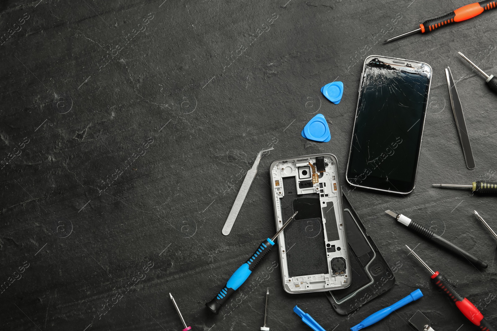 Photo of Damaged smartphone and repair tools on black background, flat lay. Space for text