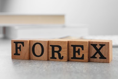 Photo of Word Forex made of wooden cubes with letters on grey table, closeup