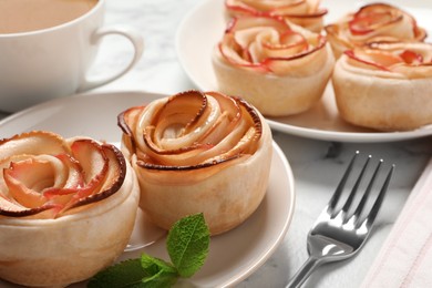 Photo of Freshly baked apple roses served on white marble table. Beautiful dessert