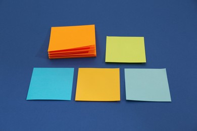 Photo of Different colorful sticky notes on blue background