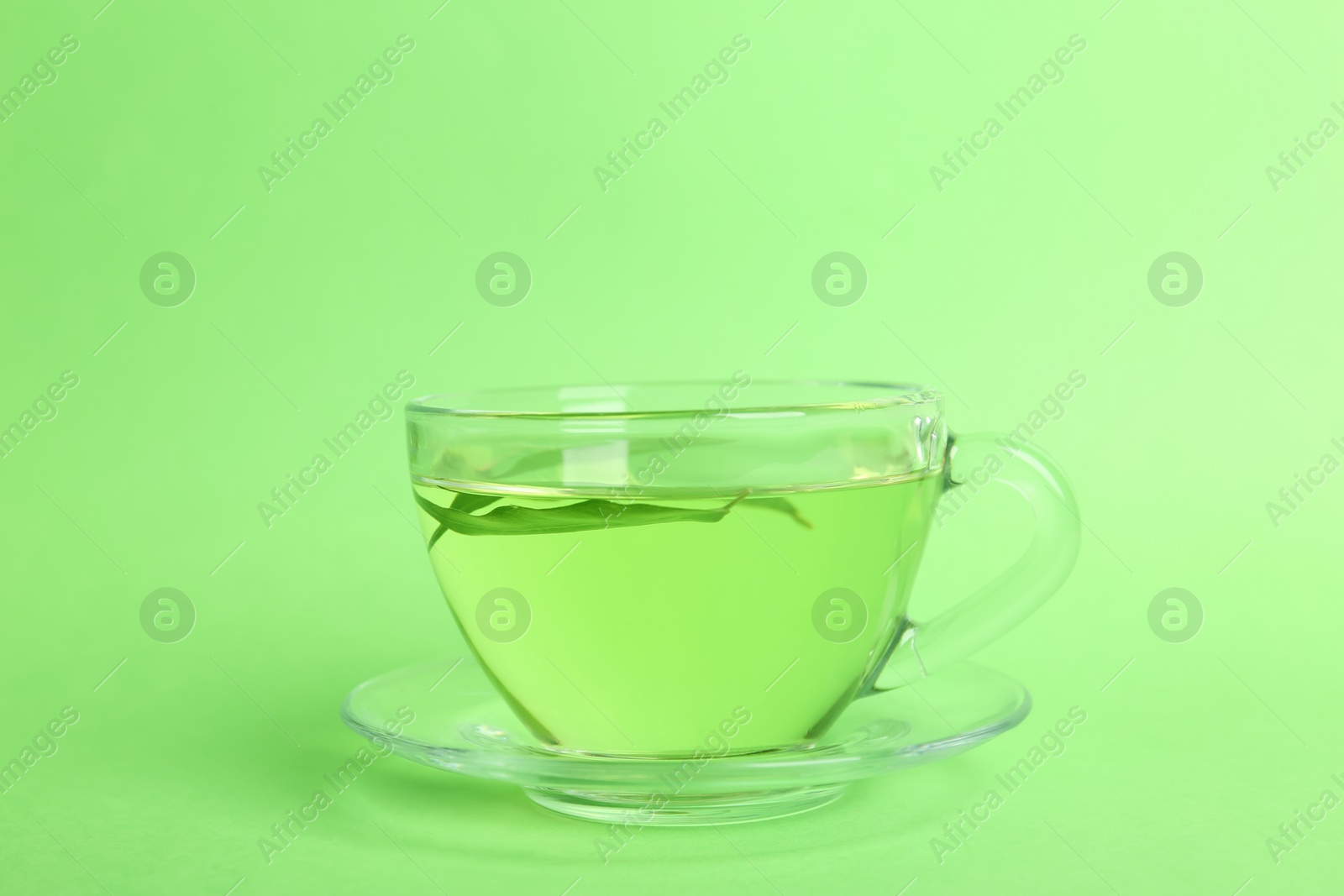 Photo of Cup of aromatic green tea with leaves on color background