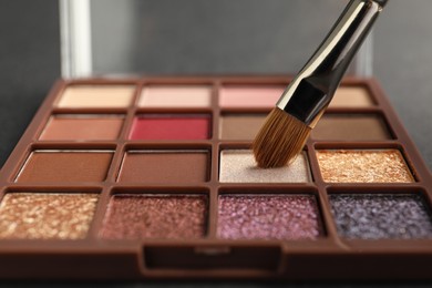 Photo of Colorful eyeshadow palette with brush, closeup view