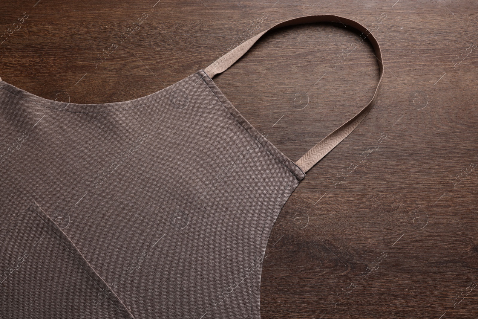 Photo of Stylish brown apron on wooden table, top view. Mockup for design