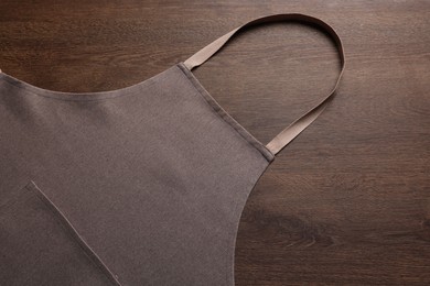 Stylish brown apron on wooden table, top view. Mockup for design