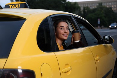Photo of Beautiful young woman with cup of coffee in taxi outdoors