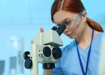 Photo of Female scientist using microscope in chemistry laboratory, space for text