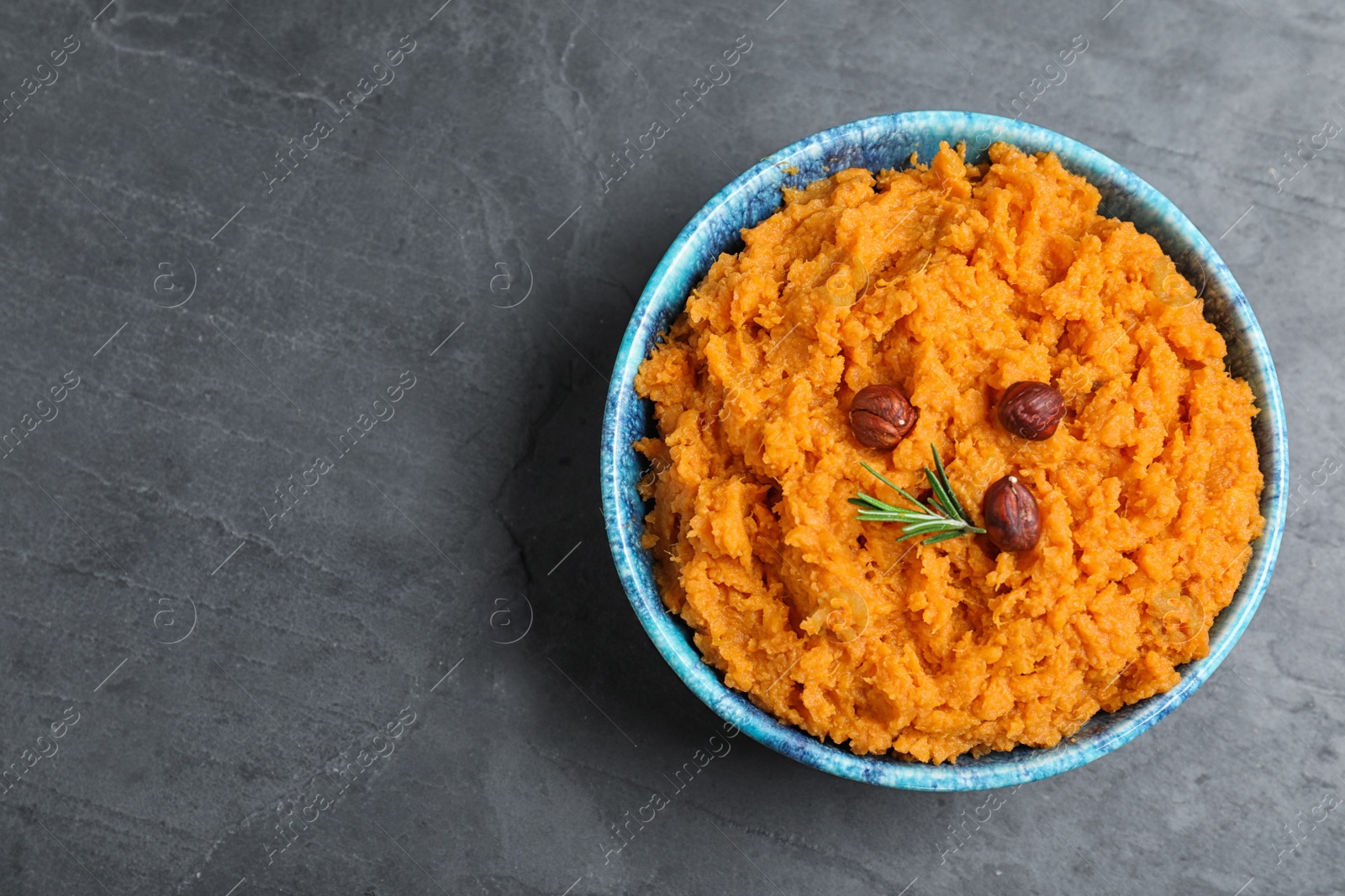 Photo of Bowl with mashed sweet potatoes on grey background, top view. Space for text