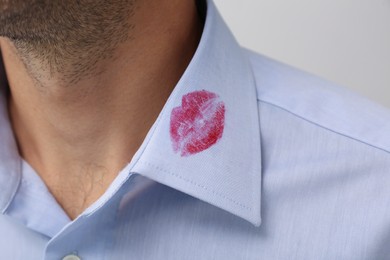 Photo of Man in shirt with lipstick kiss mark on white background, closeup
