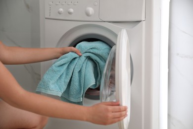 Photo of Woman putting dirty laundry into washing machine indoors, closeup