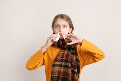 Photo of Sick little girl using nasal sprays on beige background