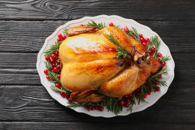 Photo of Platter of cooked turkey with garnish on wooden background, top view