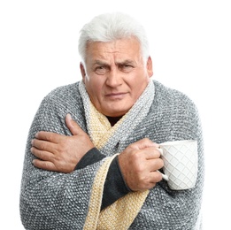 Mature man with cup of hot beverage suffering from cold on white background