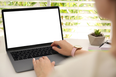 Photo of Woman working with modern laptop at white table, closeup. Space for design