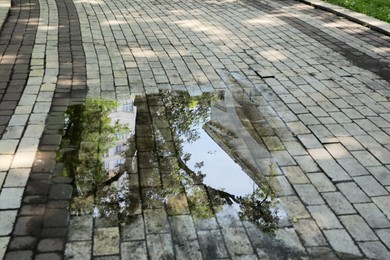 Photo of Puddle after rain on street tiles outdoors