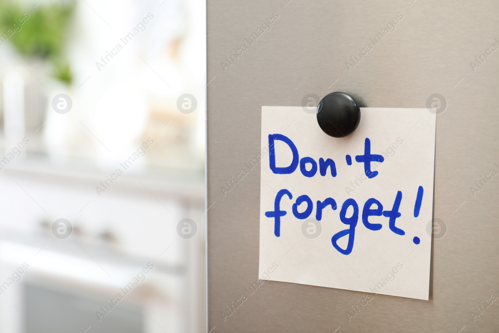 Photo of Note with text "Don't forget" and magnet on refrigerator door in kitchen. Space for text