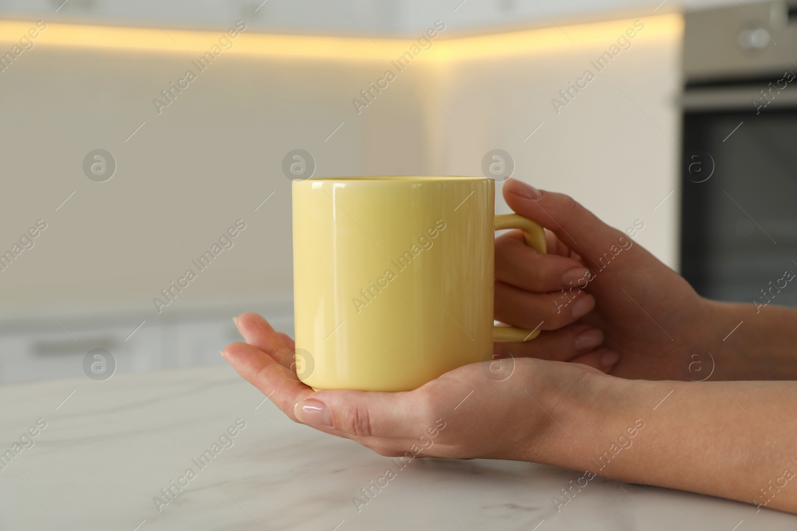 Photo of Woman with yellow cup at table indoors, closeup