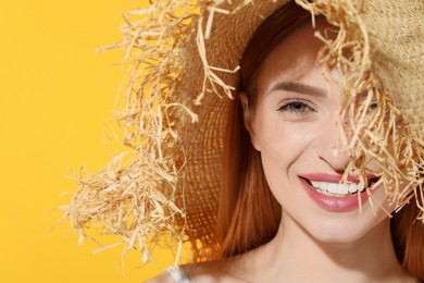 Photo of Beautiful young woman in straw hat on orange background, closeup. Space for text