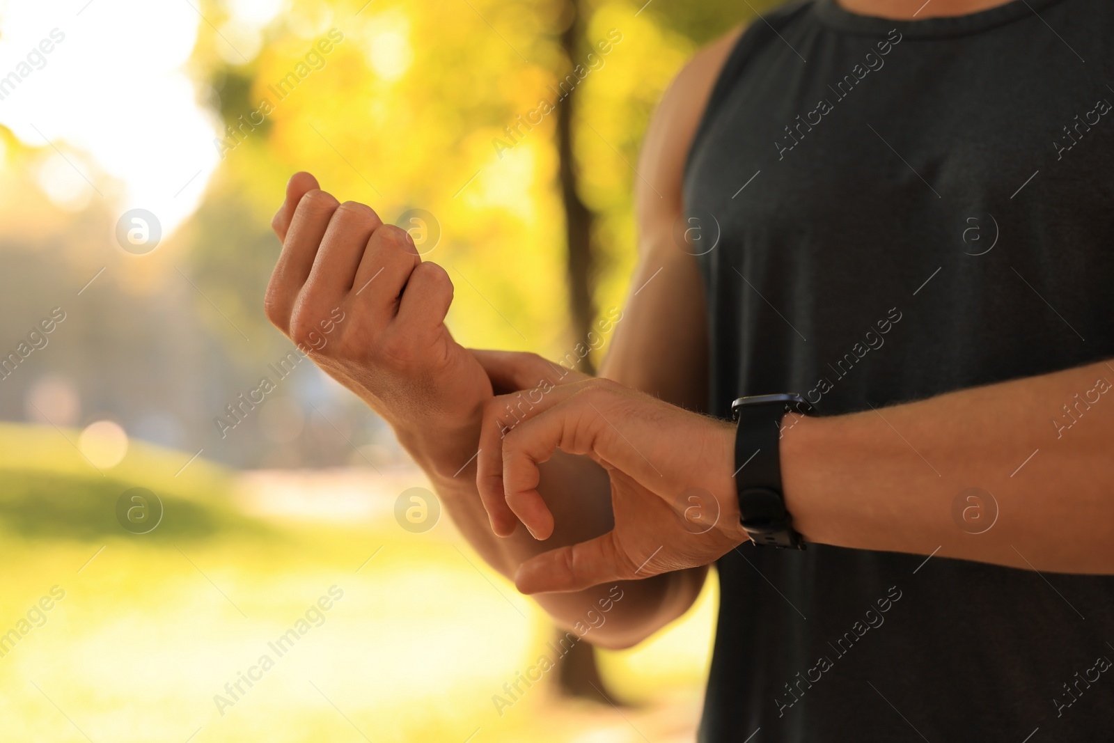 Photo of Man checking pulse after training on sunny day, closeup