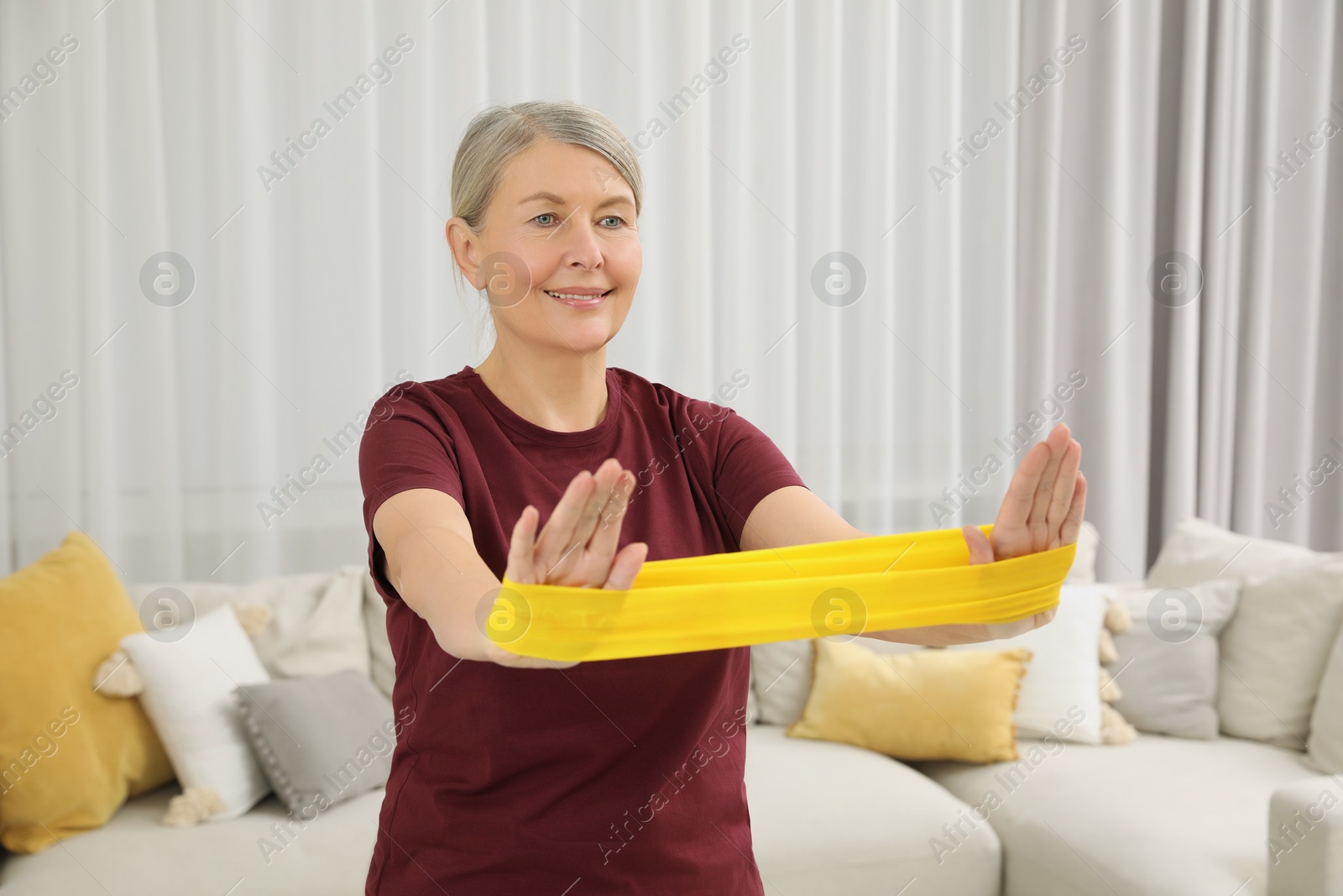 Photo of Senior woman doing exercise with fitness elastic band at home