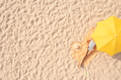 Image of Woman resting under yellow beach umbrella at sandy coast, aerial view. Space for text
