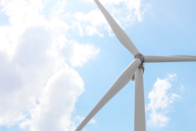 Modern wind turbine against blue sky, low angle view. Energy efficiency