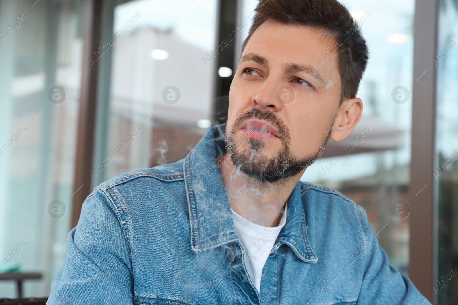 Photo of Handsome mature man smoking outdoors. Bad habit