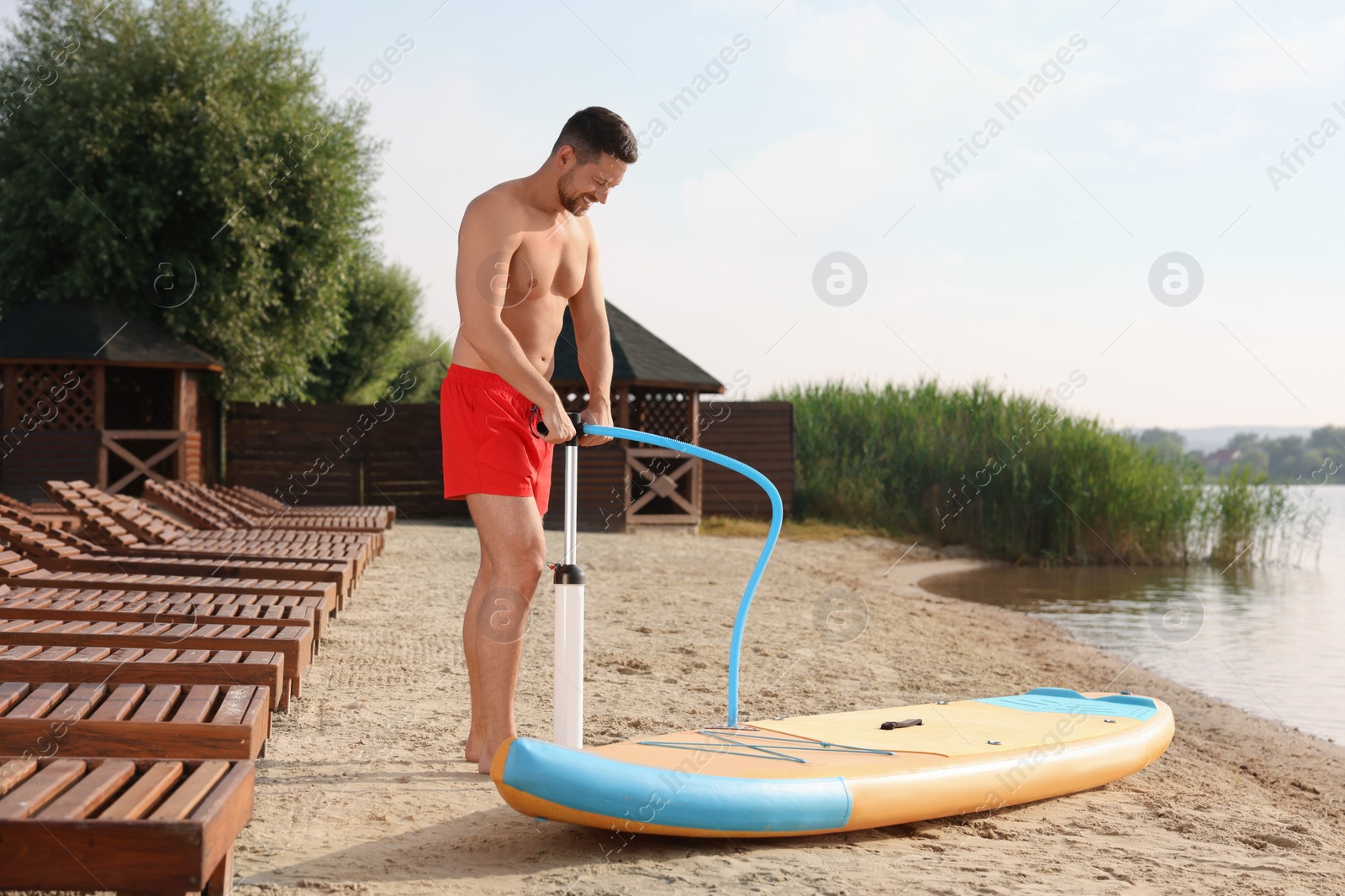 Photo of Man pumping up SUP board on river shore