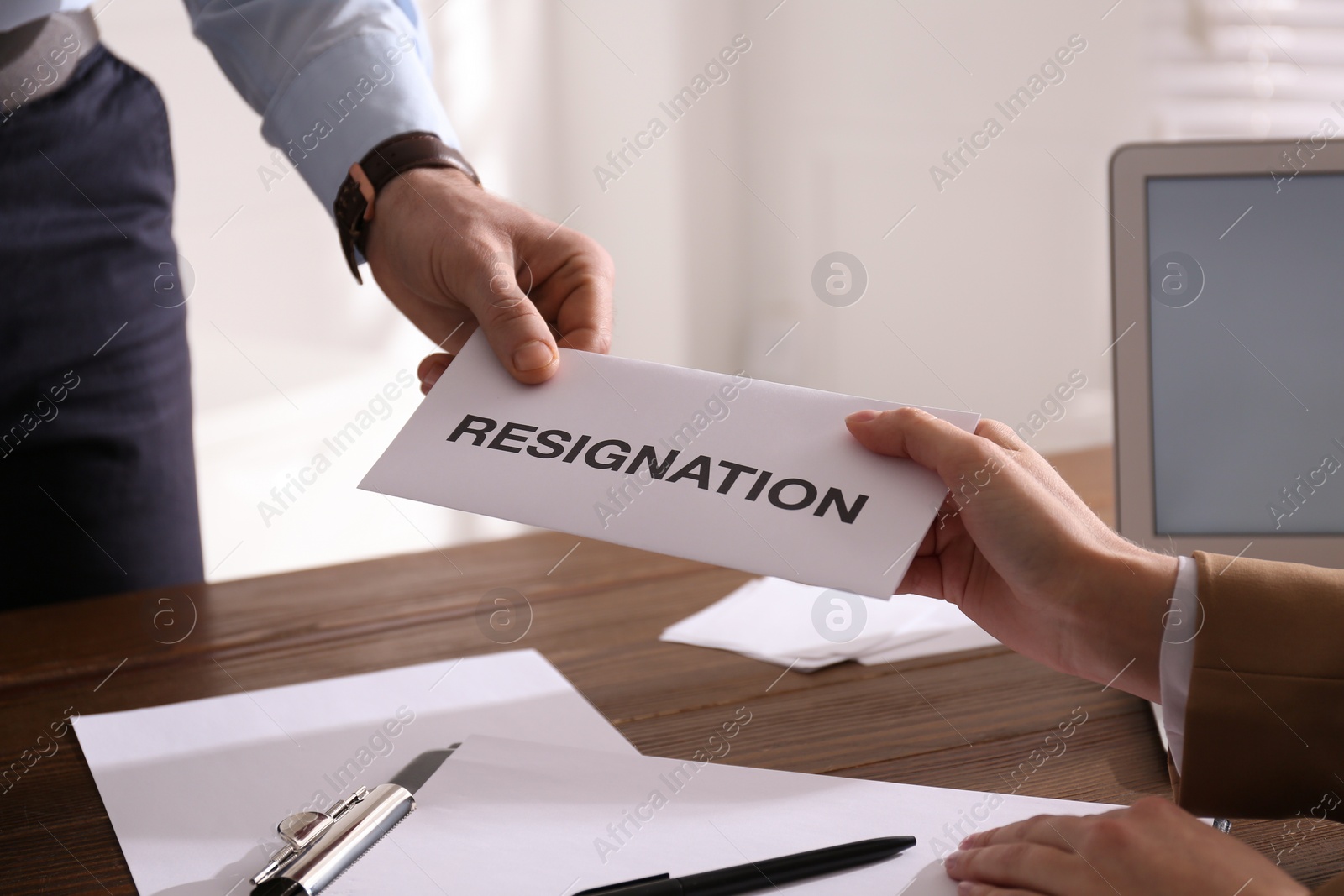 Photo of Employee giving resignation letter to boss in office, closeup