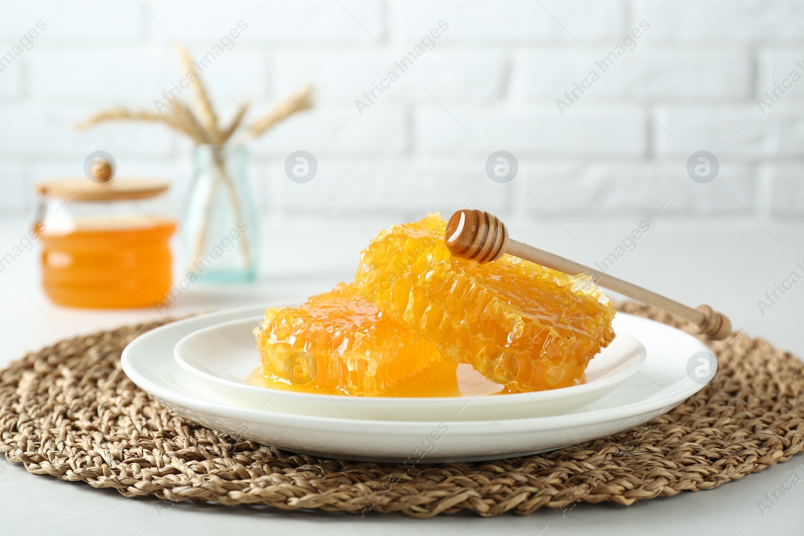 Photo of Natural honeycombs with tasty honey and dipper on white table