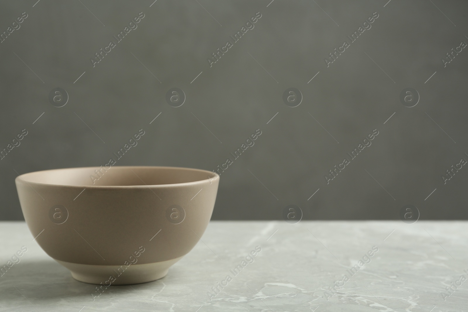 Photo of Stylish empty ceramic bowl on grey table, space for text. Cooking utensil