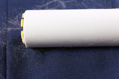 Photo of Removing hair from blue fabric with lint roller, closeup