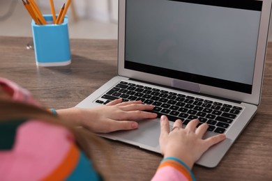 Photo of E-learning. Girl using laptop during online lesson at table indoors, closeup