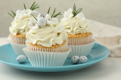 Tasty Easter cupcakes with vanilla cream on light wooden table, closeup