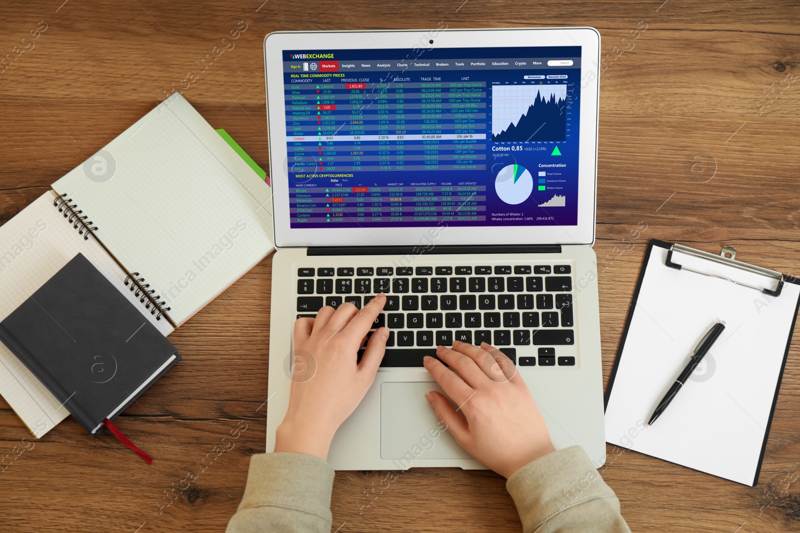 Image of Woman analyzing electronic trading platform on laptop at wooden table, above view. Stock exchange