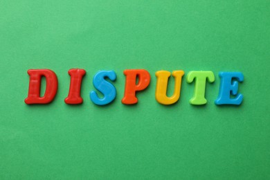 Word Dispute made of colorful letters on green background, flat lay
