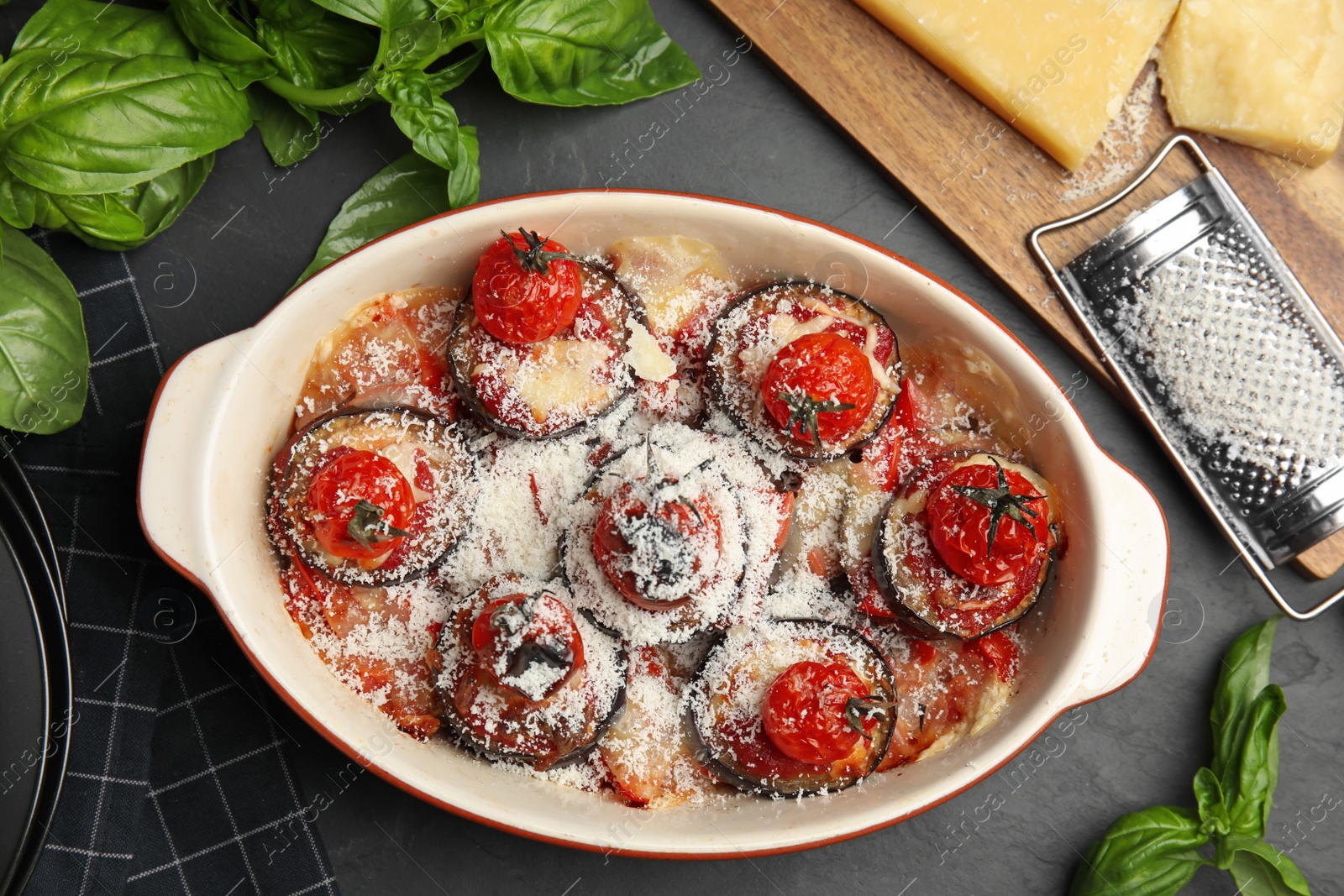 Photo of Baked eggplant with tomatoes and cheese served on black table, flat lay
