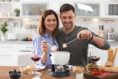 Happy couple enjoying fondue dinner at home