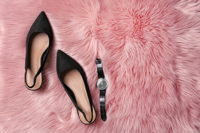 Photo of Pair of female shoes and wristwatch on fur, top view