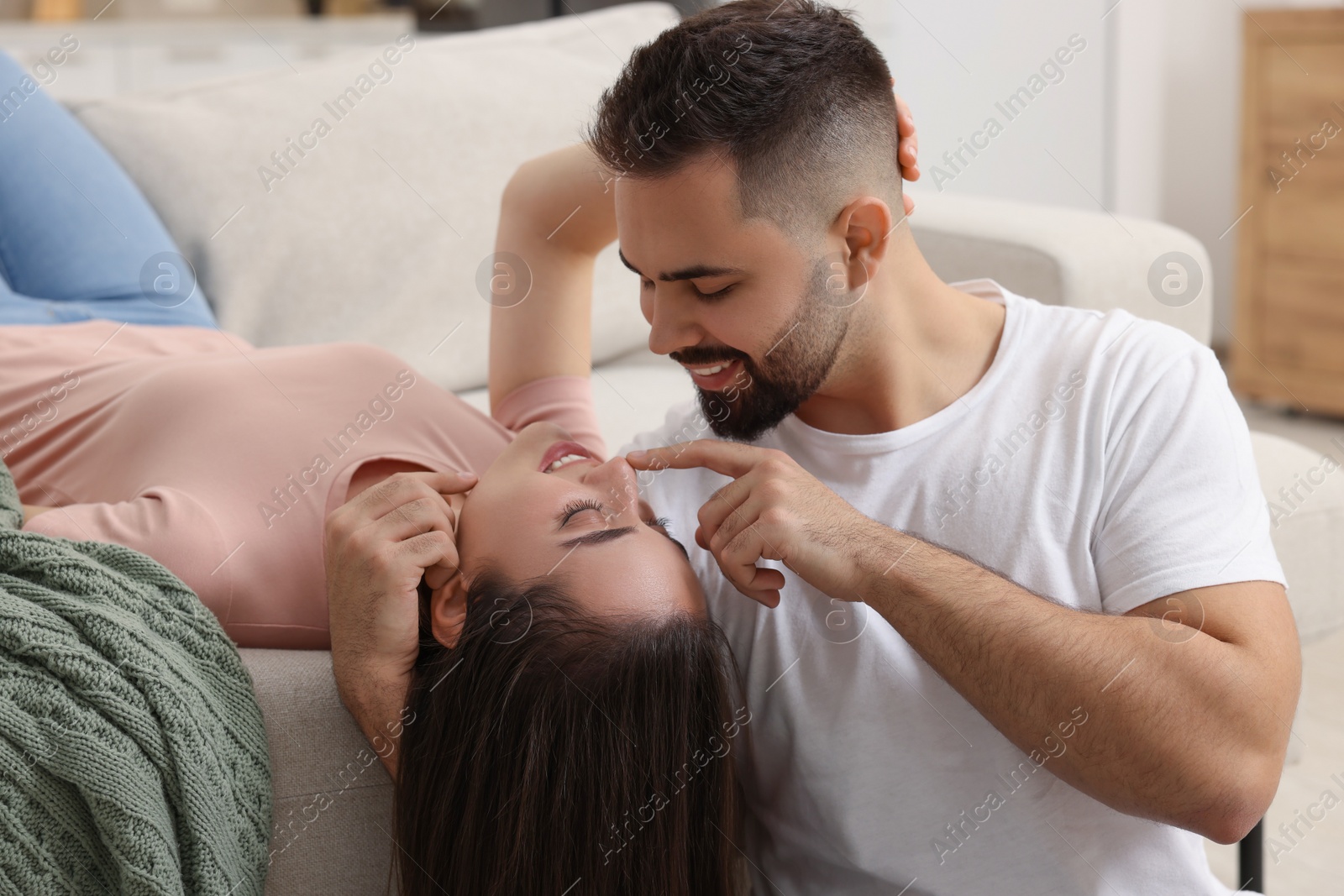 Photo of Affectionate young couple spending time together on sofa indoors