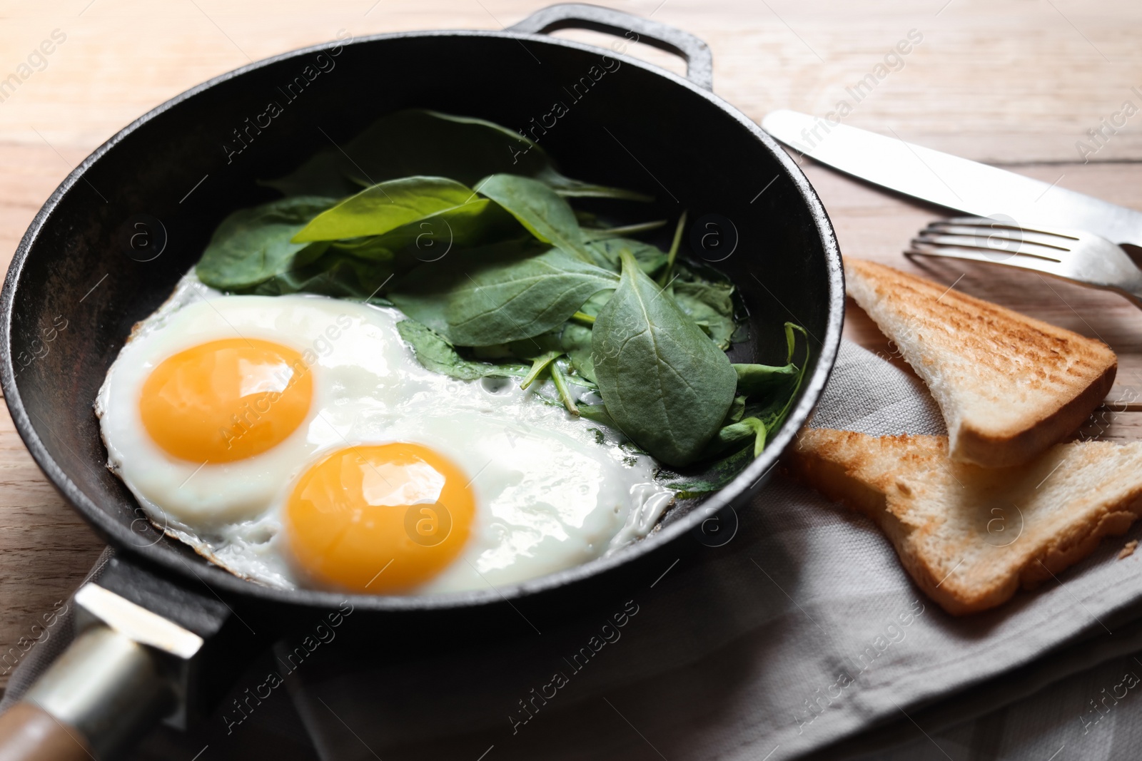 Photo of Delicious fried egg with spinach served on wooden table, closeup