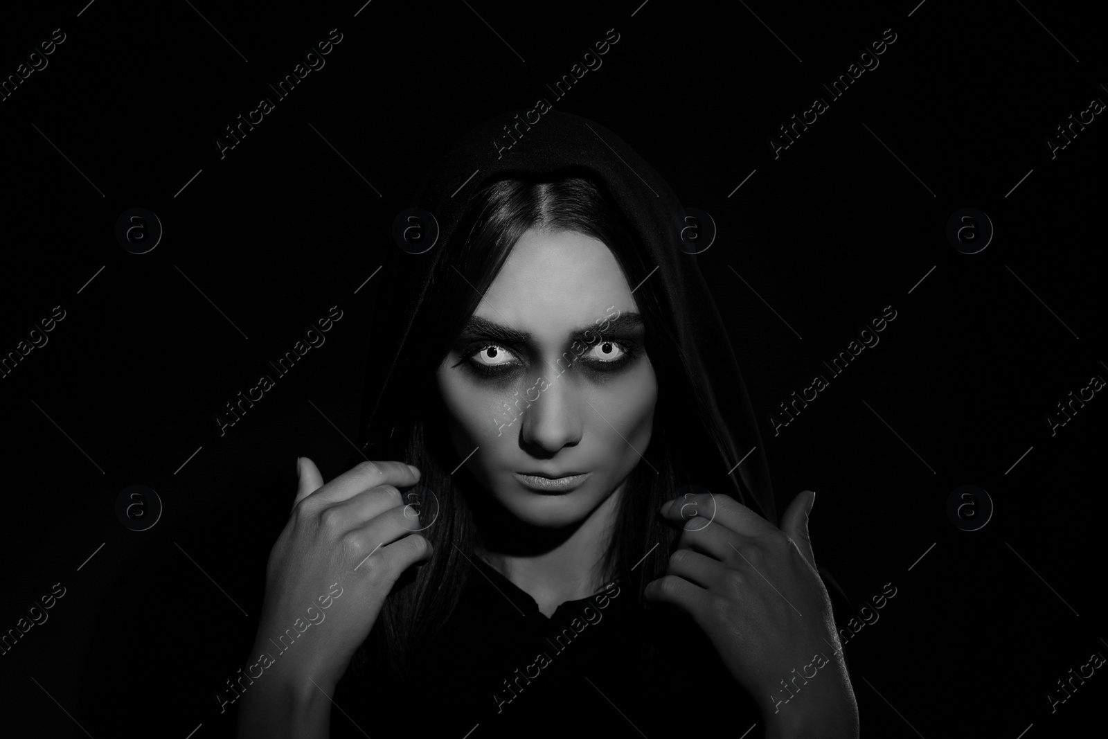 Photo of Mysterious witch with spooky eyes on dark background. Black and white effect